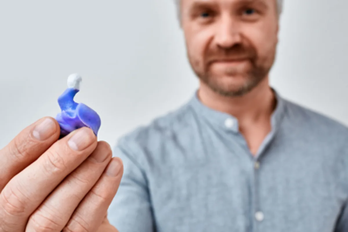 a man holding a custom ear mold