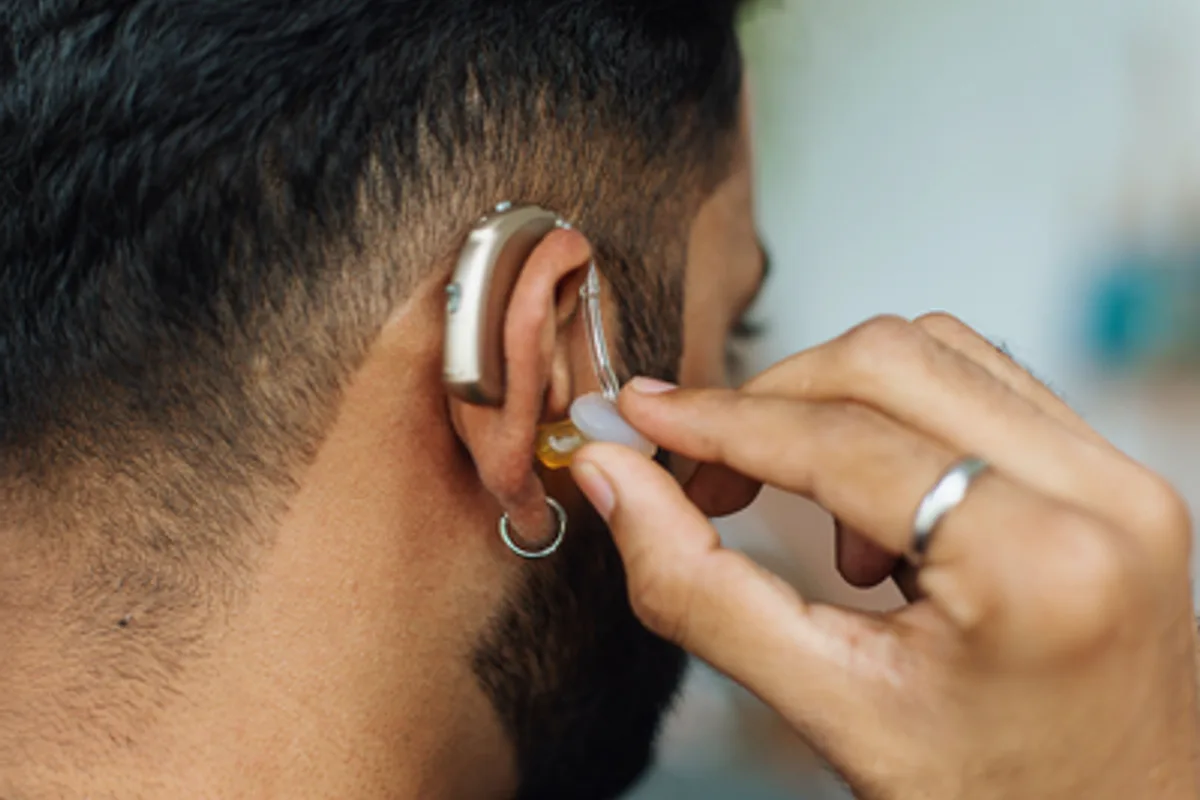 close up of a man adjusting his hearing aid