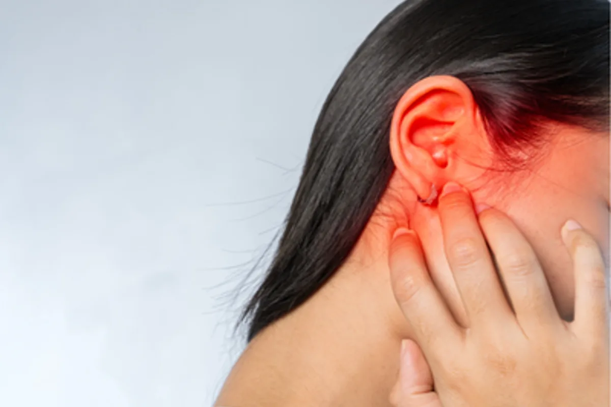 woman holding her ear which is glowing red indicating pain