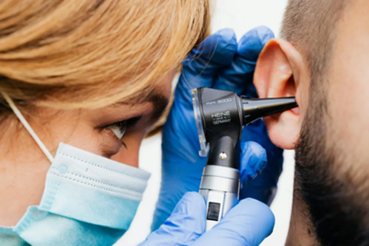audiologist looking in a patient's ear with an otoscope